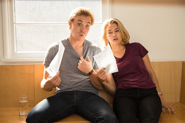Uncomfortable couple sitting in house that is too hot