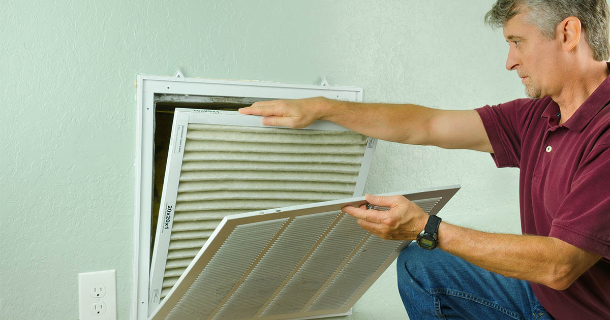 Articles : Man changing his air conditioner filter to maintain the system